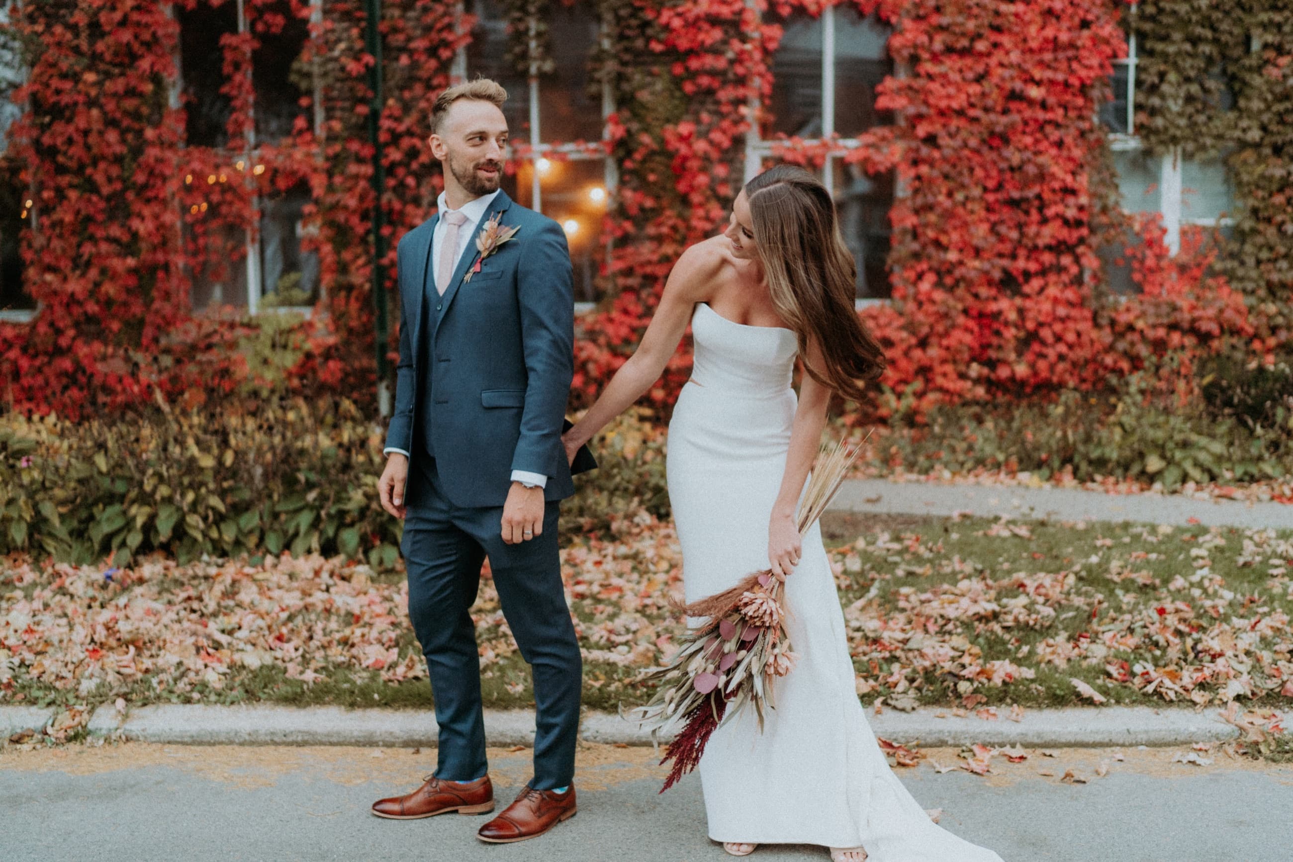 Couple walking in front of red ivy on their wedding day