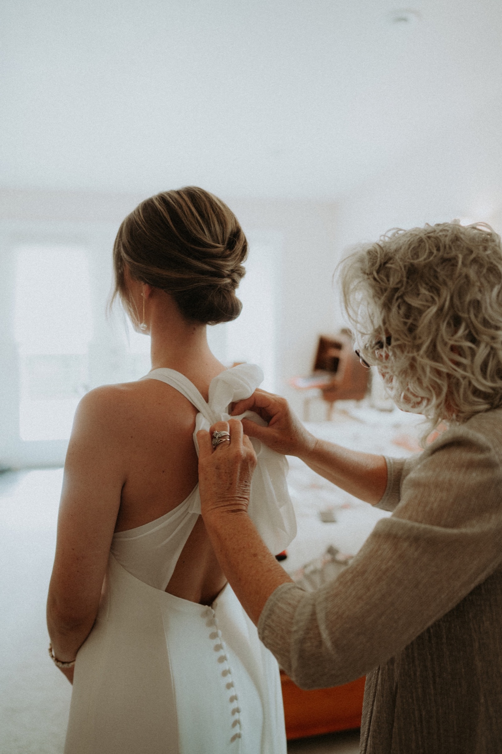 A mother helping her daughter with her wedding dress
