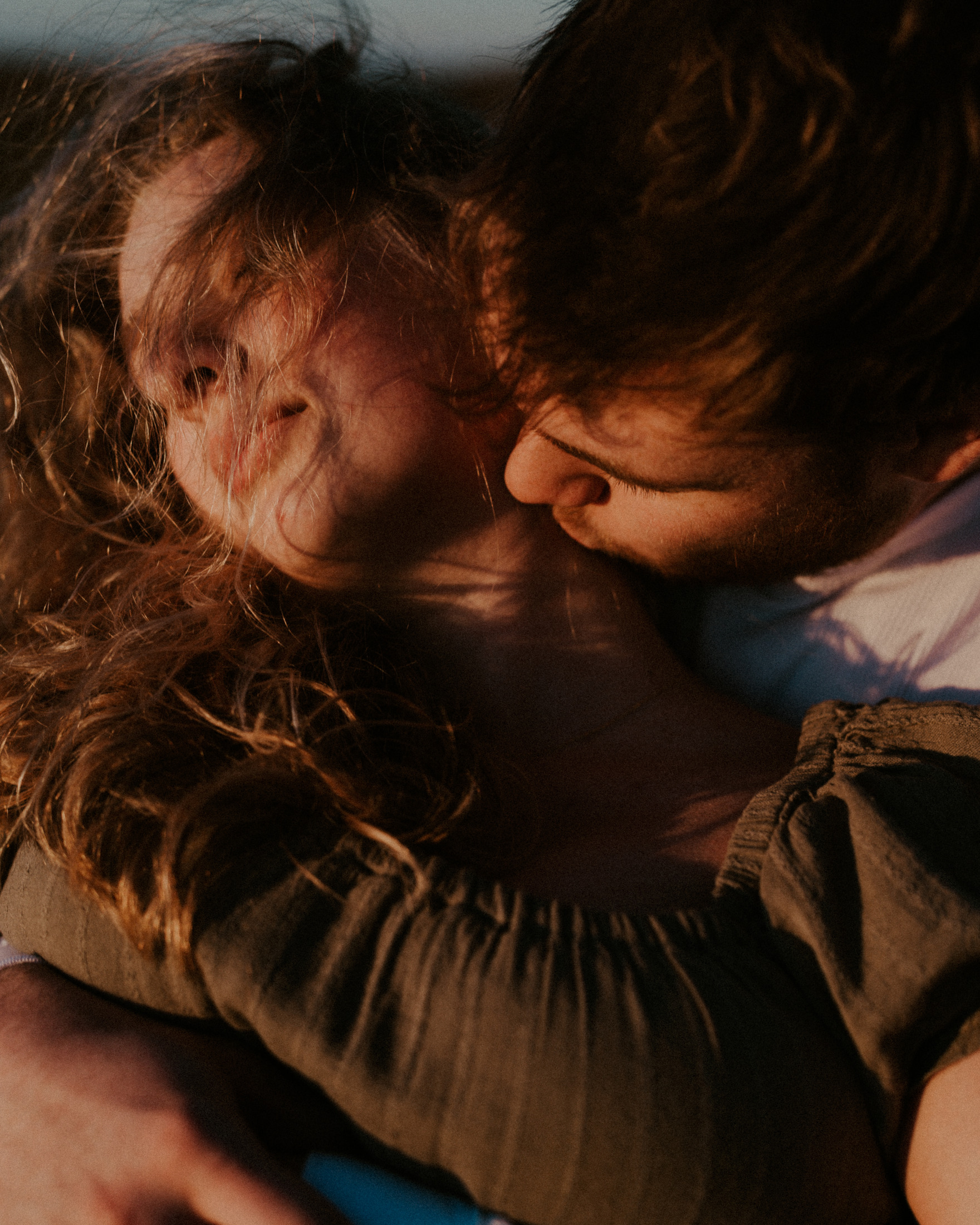 Gabe embracing Alena as she closes her eyes in evening light