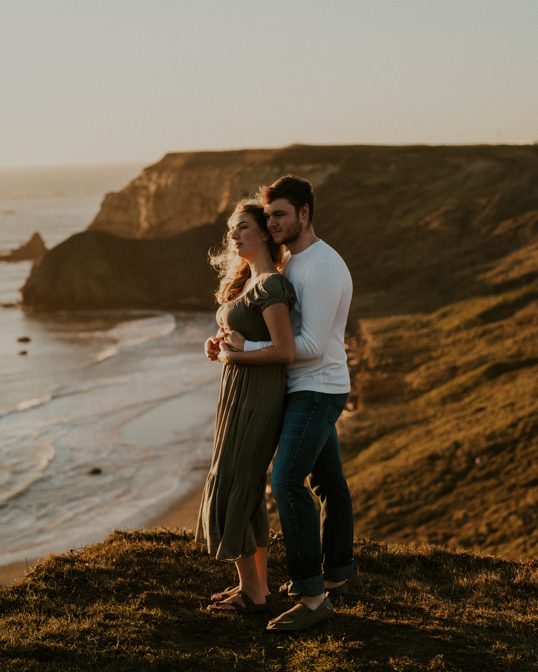 Gabe and Alena standing together above the beach in evening light