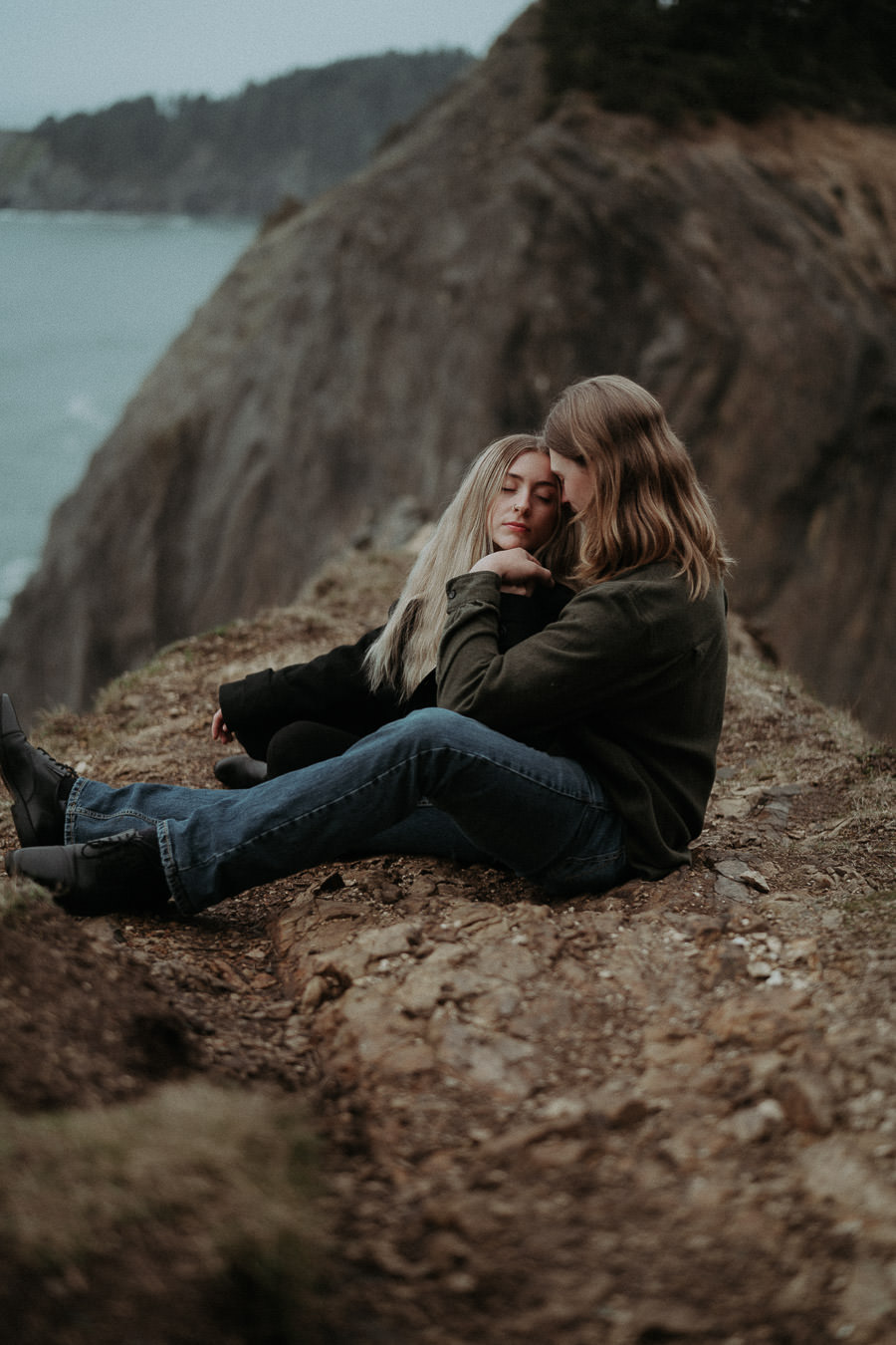 Hannah leaning back against Clay on a coastal hillside