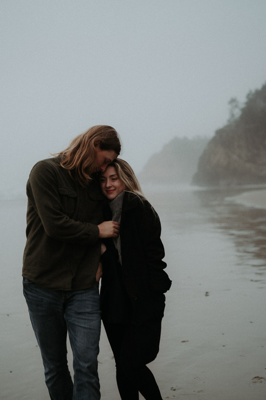 Hannah laughing as she walks barefoot beside Clay along the beach