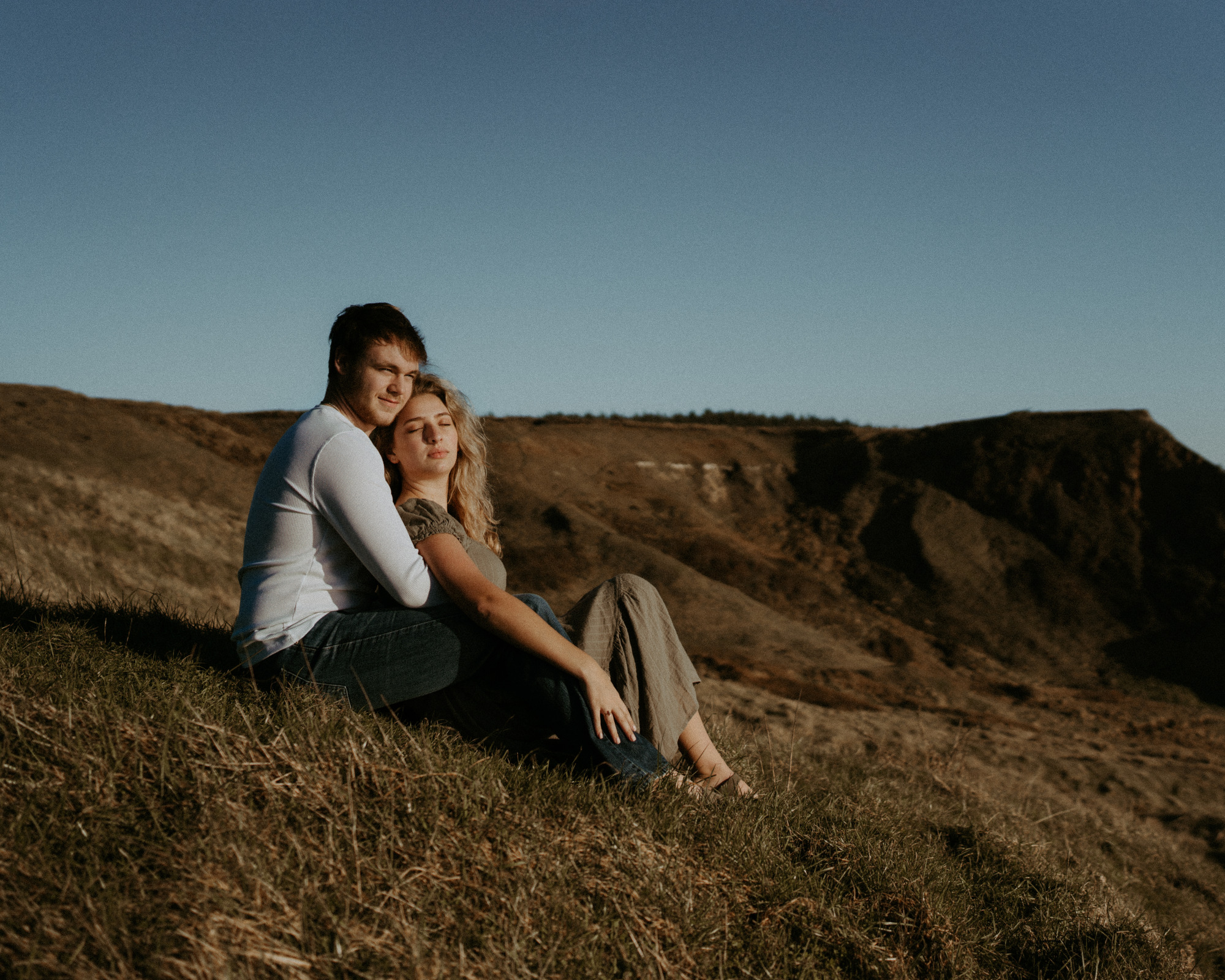 Gabe and Alena sitting together above an Oregon beach