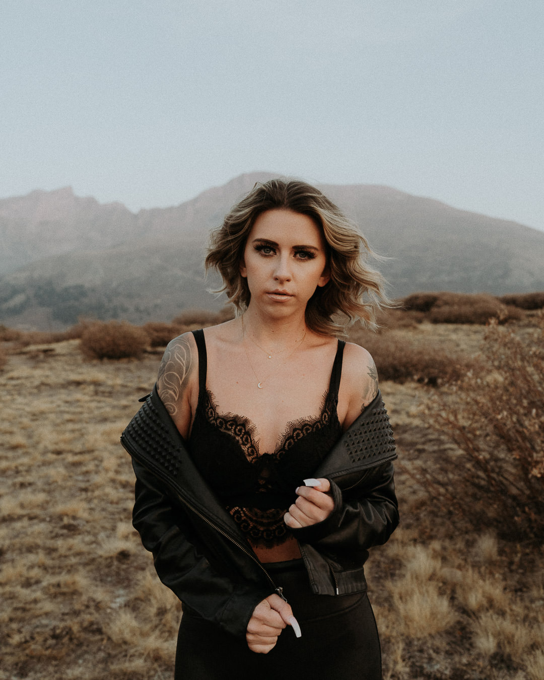 A woman in a black jacket photographed against a mountain landscape