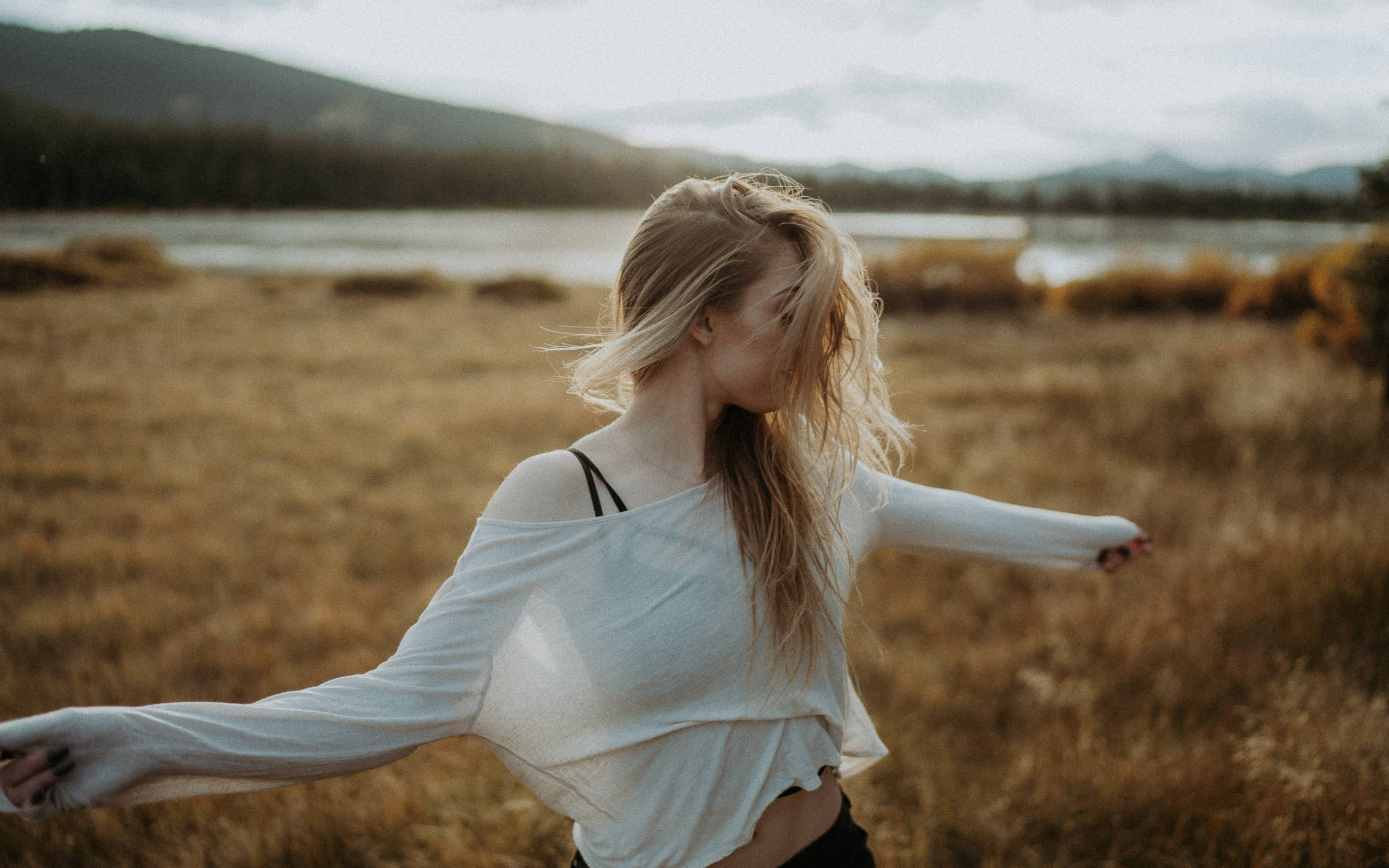A woman turning in a mountain meadow with her shirt moving in the breeze
