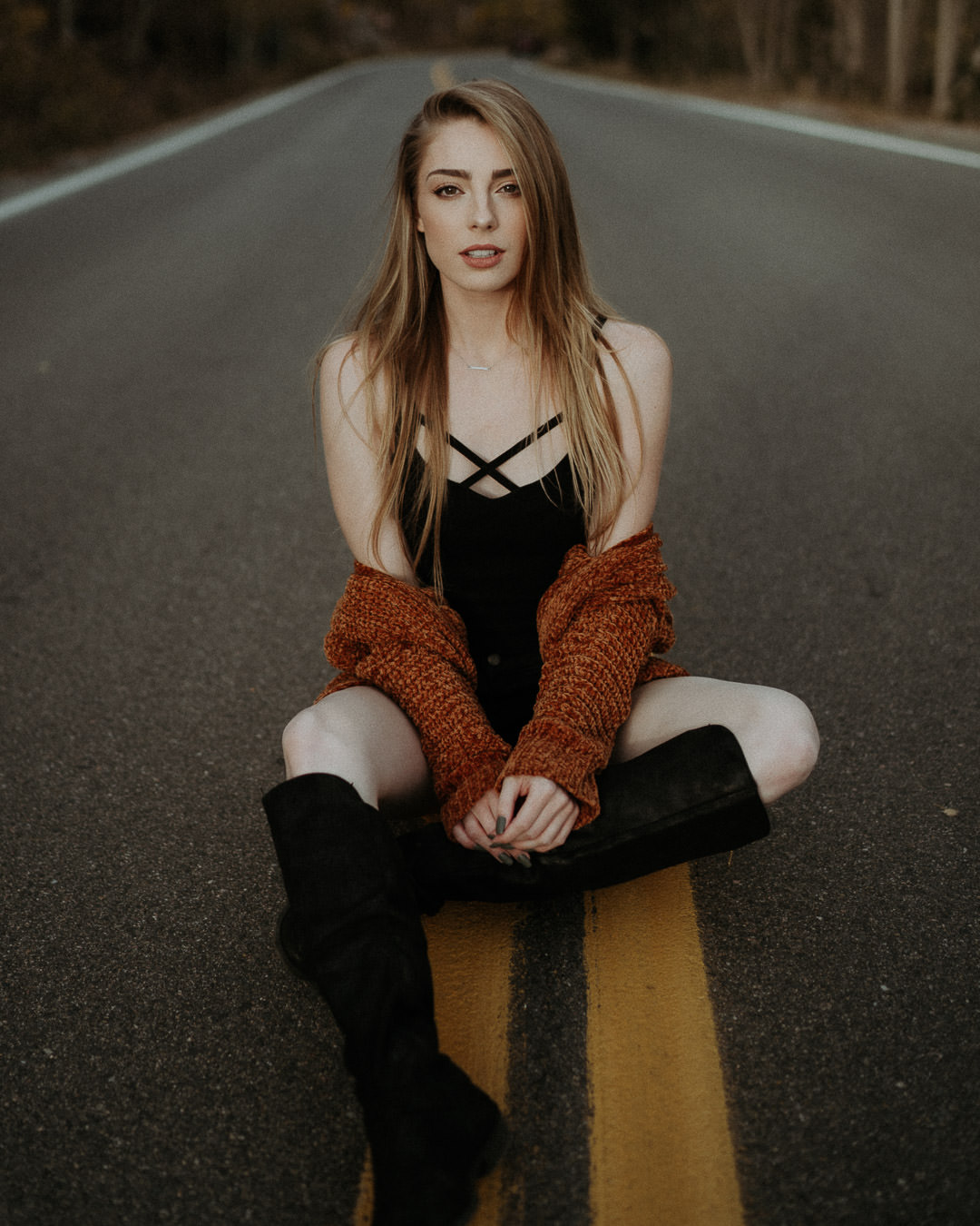 A woman seated on the center line of a mountain road