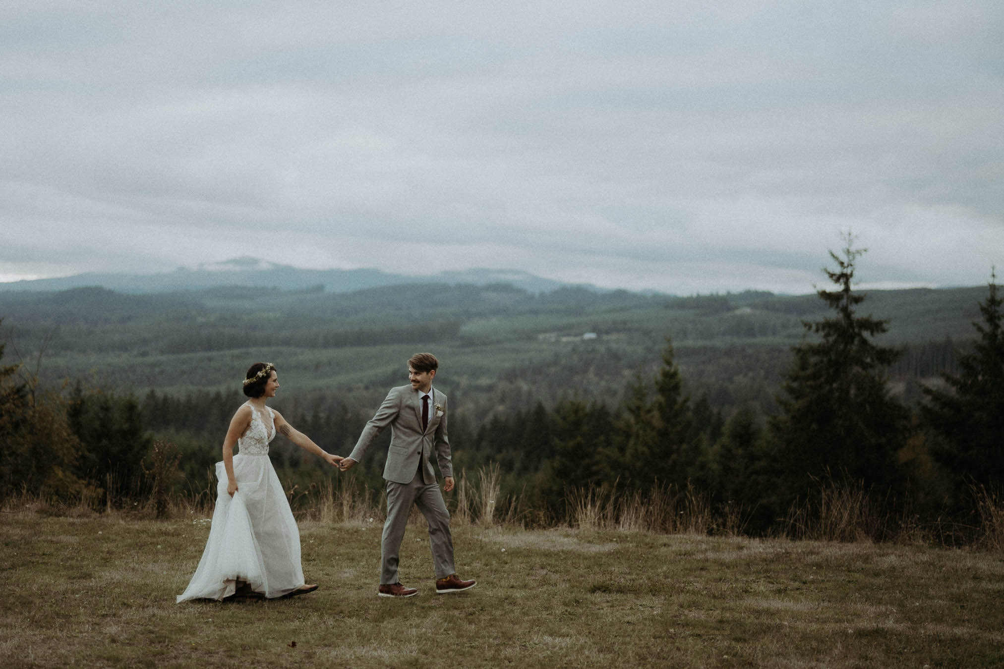 Newlyweds turning toward each other in a clearing above the Oregon forest