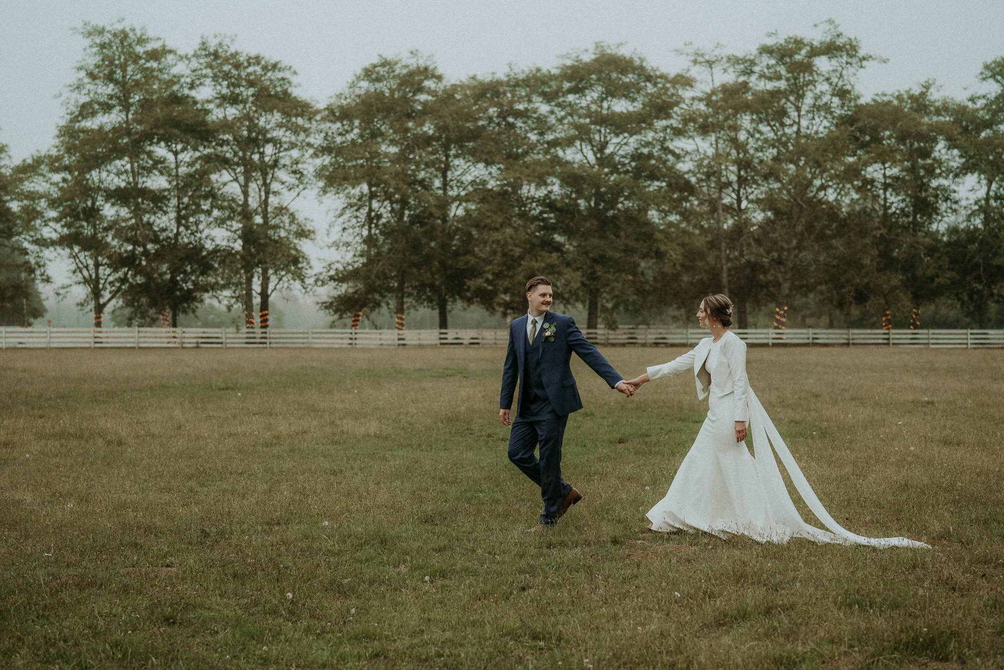 Newlyweds walking through an open field